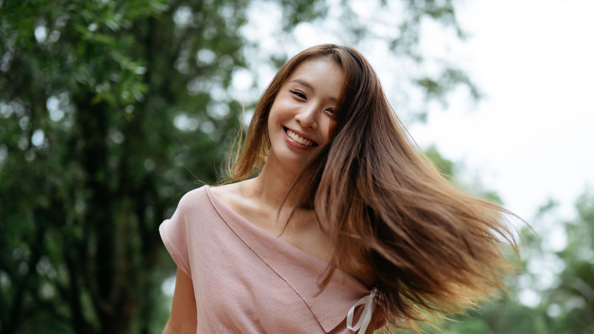 Smiling woman with flowing hair outdoors.